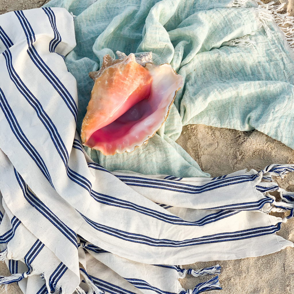 Cozy Koza Beach towels on the sand with a sea shell